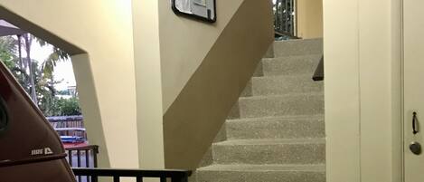 A staircase with a metal railing, a door, and a wall-mounted bulletin board.