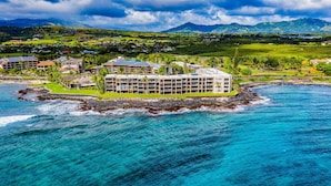 Un hotel sulla costa con diversi edifici, una linea di costa rocciosa e vista sull'oceano e sulle montagne sullo sfondo.