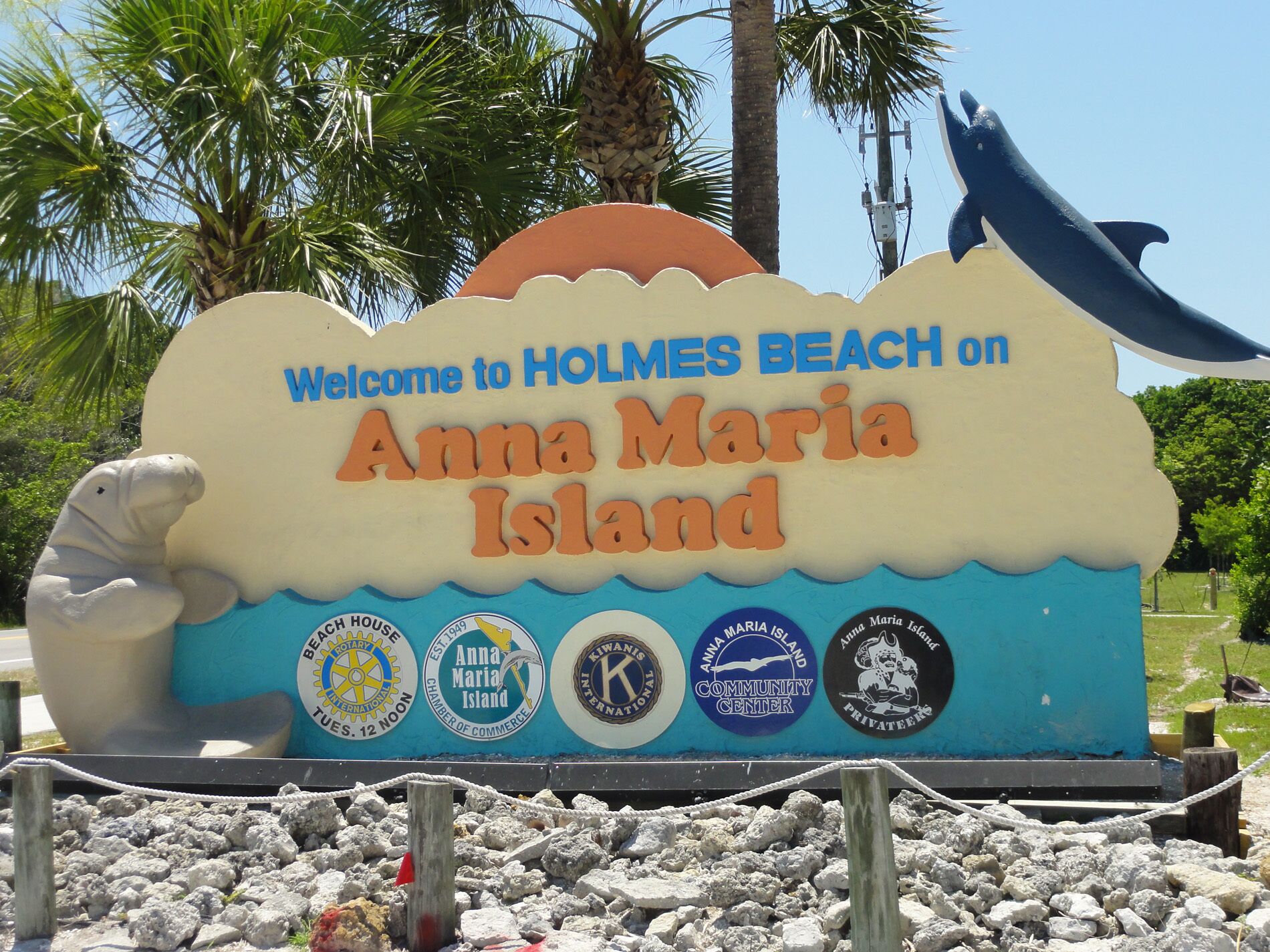 A welcome sign for Anna Maria Island with a seal and various logos.