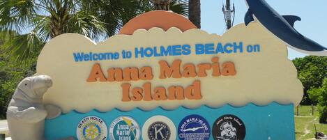 A welcome sign for Anna Maria Island with a seal and various logos.