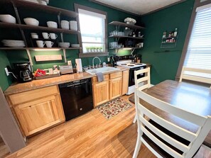 A kitchen with wooden cabinets, a dishwasher, a sink, and a window. - Walker's Place, Historic Home, Downtown Whitefish! (Whitefish)