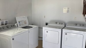 A laundry room with two front-loading washers and a dryer, a control panel, and a sign with laundry instructions. - 21-- St George Condo 1king, 1Queen, fold down chair -pool, hot tub. (St. George)