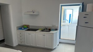 Een keuken met witte kasten, een zwart aanrecht, een spoelbak en een koelkast.