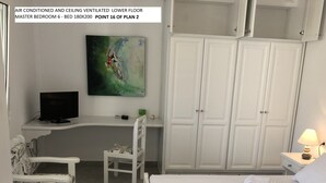 Een hoofdslaapkamer met een groot bed, een bureau, een stoel en een kledingkast.