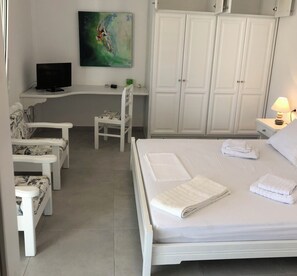 Une chambre principale dotée d’un grand lit, d’un bureau, d’une chaise et d’une armoire.