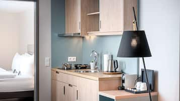 A compact kitchen with wooden cabinets, a sink, a kettle, and a coffee maker.
