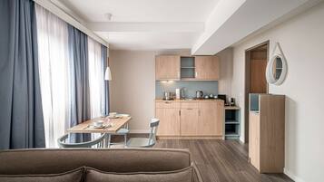 Habitación de hotel compacta con kitchenette, zona de comedor y sofá.