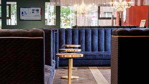 A seating area with dark blue upholstered sofas and a central round table with a gold base. - elaya hotel oberhausen, Trademark by Wyndham (Oberhausen)