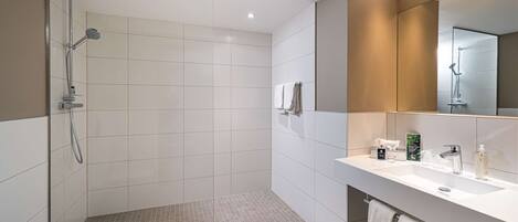 Un baño moderno con cabina de ducha, espejo grande y tocador con lavabo y toallero.