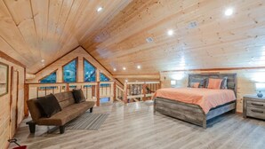 Ruime loft slaapkamer met een groot bed, houten plafond en uitzicht door de ramen.