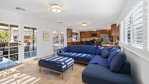 A spacious living area with a sectional sofa, a dining table, and a kitchen in the background. - Centrally located Palm Desert Oasis (Palm Desert)