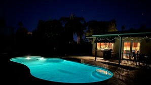 A swimming pool at night with a patio area and string lights. - Centrally located Palm Desert Oasis (Palm Desert)