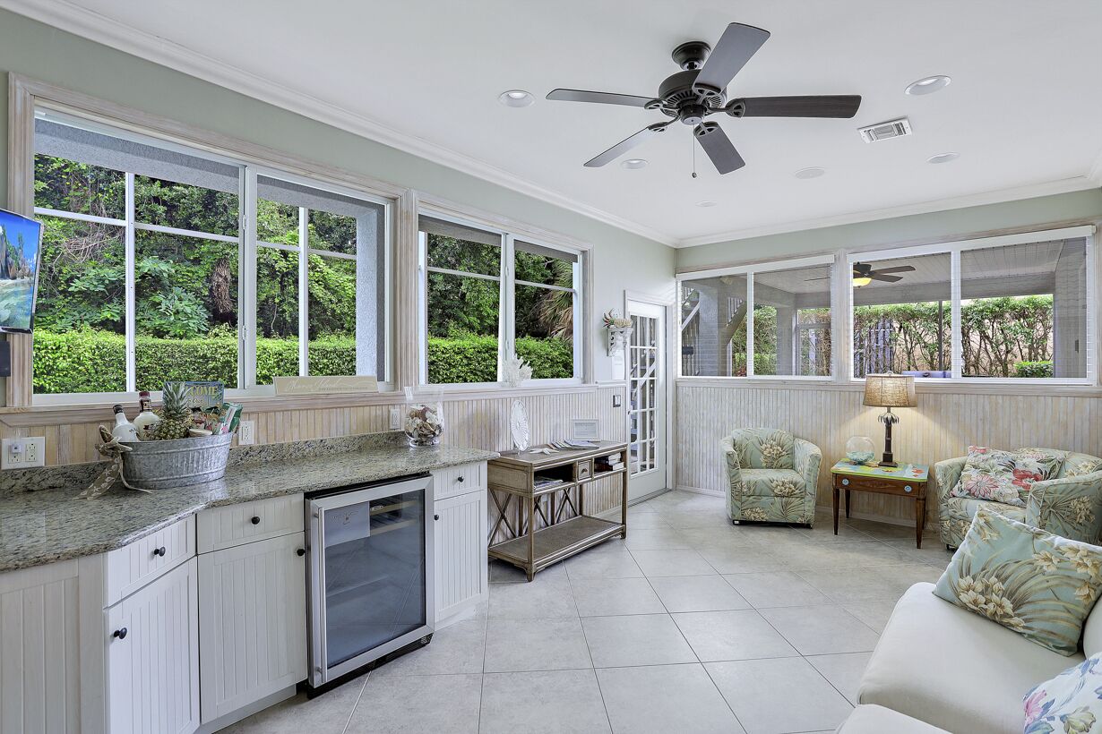 A spacious kitchen with large windows, a ceiling fan, and a cozy seating area with a lamp.
