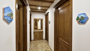 A hallway with wooden doors and a tiled floor. - Hotel Goloritzé (Baunei)