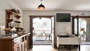 A hotel kitchen with wooden cabinets, a buffet counter, and a dining area with a table and chairs. - Hotel Goloritzé (Baunei)