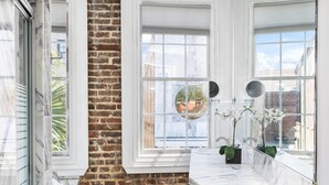 Una cocina moderna con pared de ladrillo, ventanas amplias y encimeras de mármol.