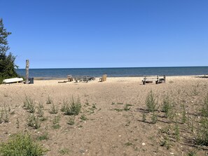 A beach with several wooden benches and a white boat on the sand.