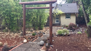 A wooden pergola in a garden with a house in the background. - Bamboo House Studio - Clean and Cozy Apartment ready just for you! (Eugene)