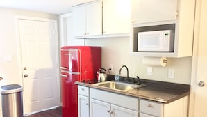 A compact kitchen with white cabinets, a red refrigerator, a stainless steel sink, and a microwave above the counter. - Bamboo House Studio - Clean and Cozy Apartment ready just for you! (Eugene)
