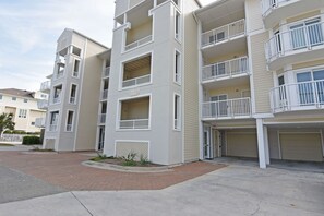 A multi-story residential building with balconies, a garage, and a brick driveway.