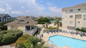 Un edificio residencial con piscina, varios balcones y un césped bien cuidado.