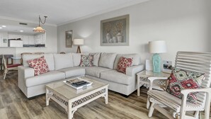 Una sala de estar moderna con un sofá modular, una mesa de centro y una zona de comedor con una silla.