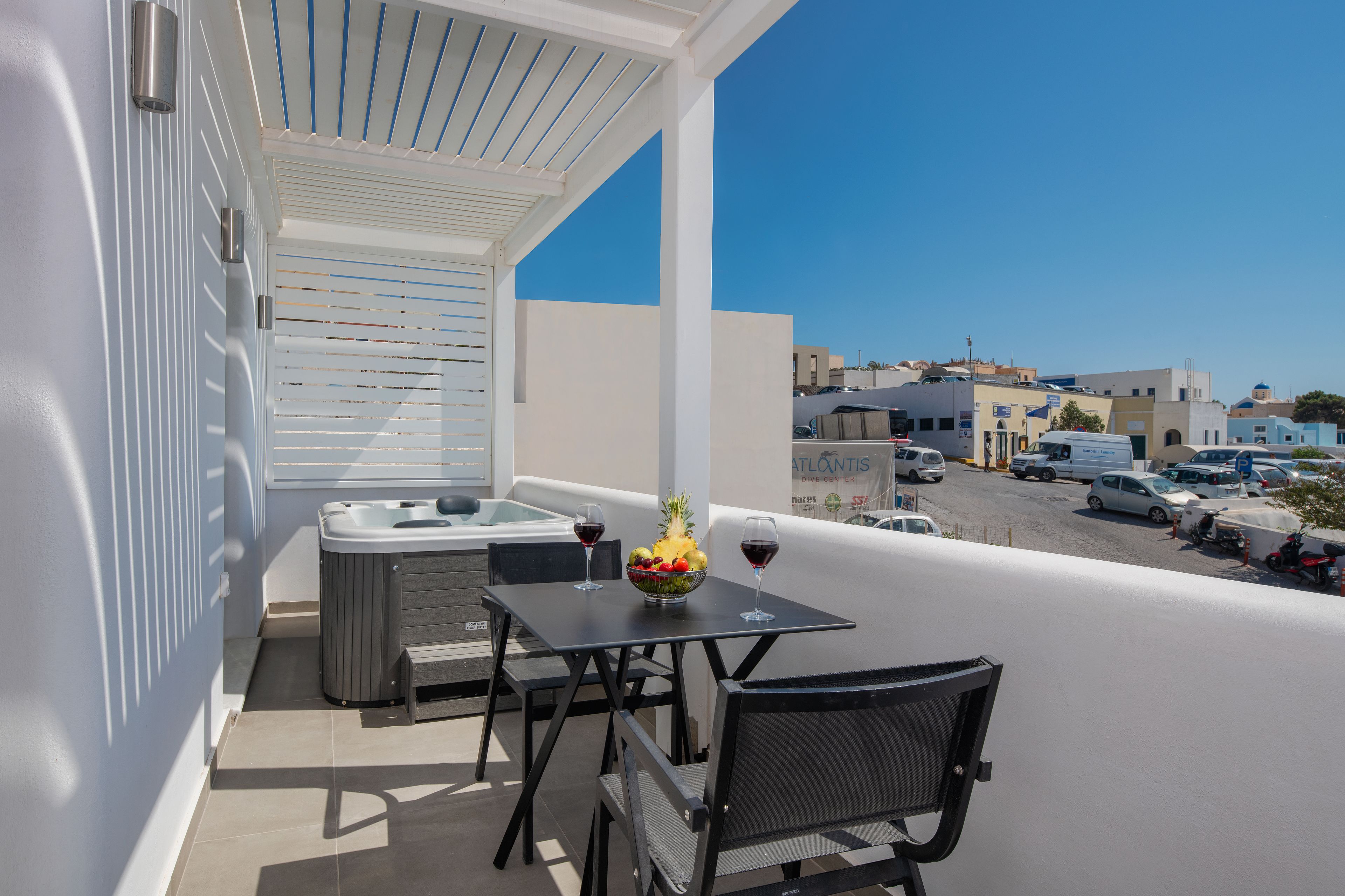 Een balkon met een tafel, stoelen en een schaal fruit.