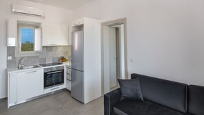 Una cocina compacta con armarios blancos, horno integrado y refrigerador.