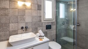Un baño moderno con un lavamanos grande de color blanco, una cabina de ducha de vidrio y un inodoro.