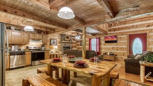 Een rustiek houten blokhut interieur met een eethoek, keuken en woongedeelte.