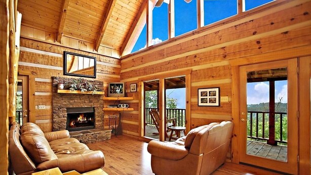 A cozy log cabin interior with a fireplace, leather sofas, and a stone accent wall. - Passion's Peak - Sleeps 2 (Sevierville)