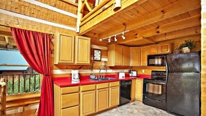 A kitchen with wooden cabinets, a red countertop, a black refrigerator, and a microwave. - Passion's Peak - Sleeps 2 (Sevierville)