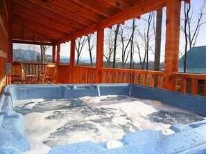 A hot tub with a wooden deck and a view of leafless trees. - Passion's Peak - Sleeps 2 (Sevierville)