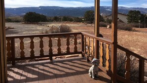 A wooden deck with a railing overlooking a dry landscape and distant mountains. - Torrey Pines Cozy Cabin! (Torrey)