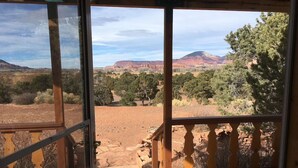 A wooden deck with a view of a desert landscape, including red rock formations and trees. - Torrey Pines Cozy Cabin! (Torrey)