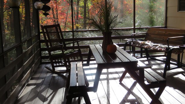 A wooden deck with benches and a table, overlooking a forest with autumn foliage. - Welcome to Owls Nest Cabin NC!<br><br>Close to Wineries, waterfalls, antique shops etc (Otto)