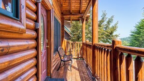 A wooden log cabin with a porch, a bench, and a door with a window. - Black Bear Ridge - 5 Bedroom minutes from the Parkway! (Sevierville)