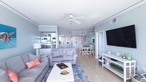 Ein modernes Wohnzimmer mit grauem Sofa, weißem Couchtisch und Fernseher an der Wand.