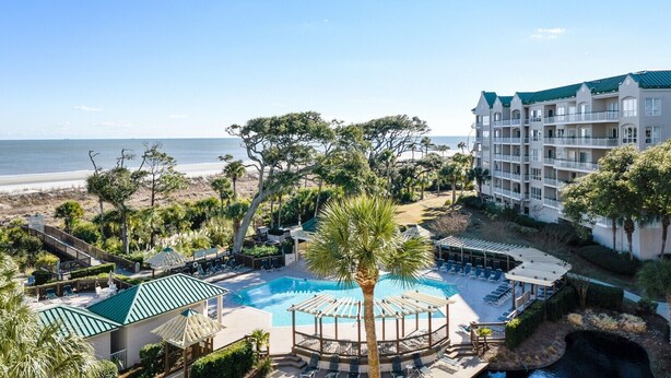 Ein Resort mit Schwimmbad, Blick auf den Strand und einem mehrstöckigen Gebäude.