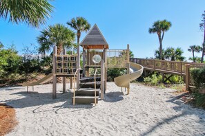 A playground with a slide, climbing area, and a small shelter.