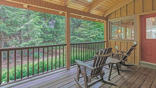 A wooden porch with a ceiling fan, two Adirondack chairs, and a view of a forested area. - Bear Den-Mountain Log Cabin, Wood Fireplace, Pool Table, Gas Grill (Seven Devils)