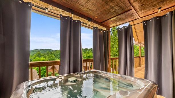 Ein Whirlpool mit Holzterrasse und Blick auf eine grüne Landschaft.