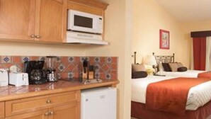 A compact hotel room with a kitchenette, a bed with an orange bedspread, and a small white refrigerator. - Christmas in paradise (Nuevo Vallarta)