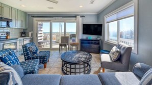 A spacious living area with a large TV, comfortable seating, and a view of the outdoors. - SeaClusion South - Oceanfront - Dog Friendly (Topsail Beach)