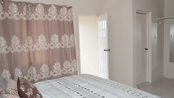 A bedroom with a bed, a curtain, and a door.