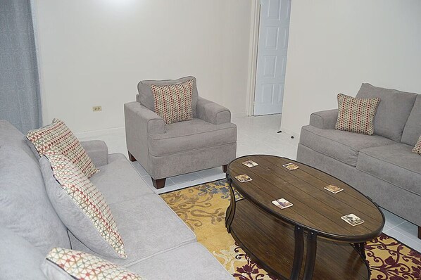 A living room with two grey sofas, a wooden coffee table, patterned cushions, and a patterned rug.