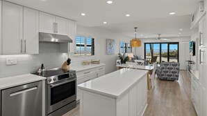 A modern kitchen with white cabinetry, stainless steel appliances, and a large island.