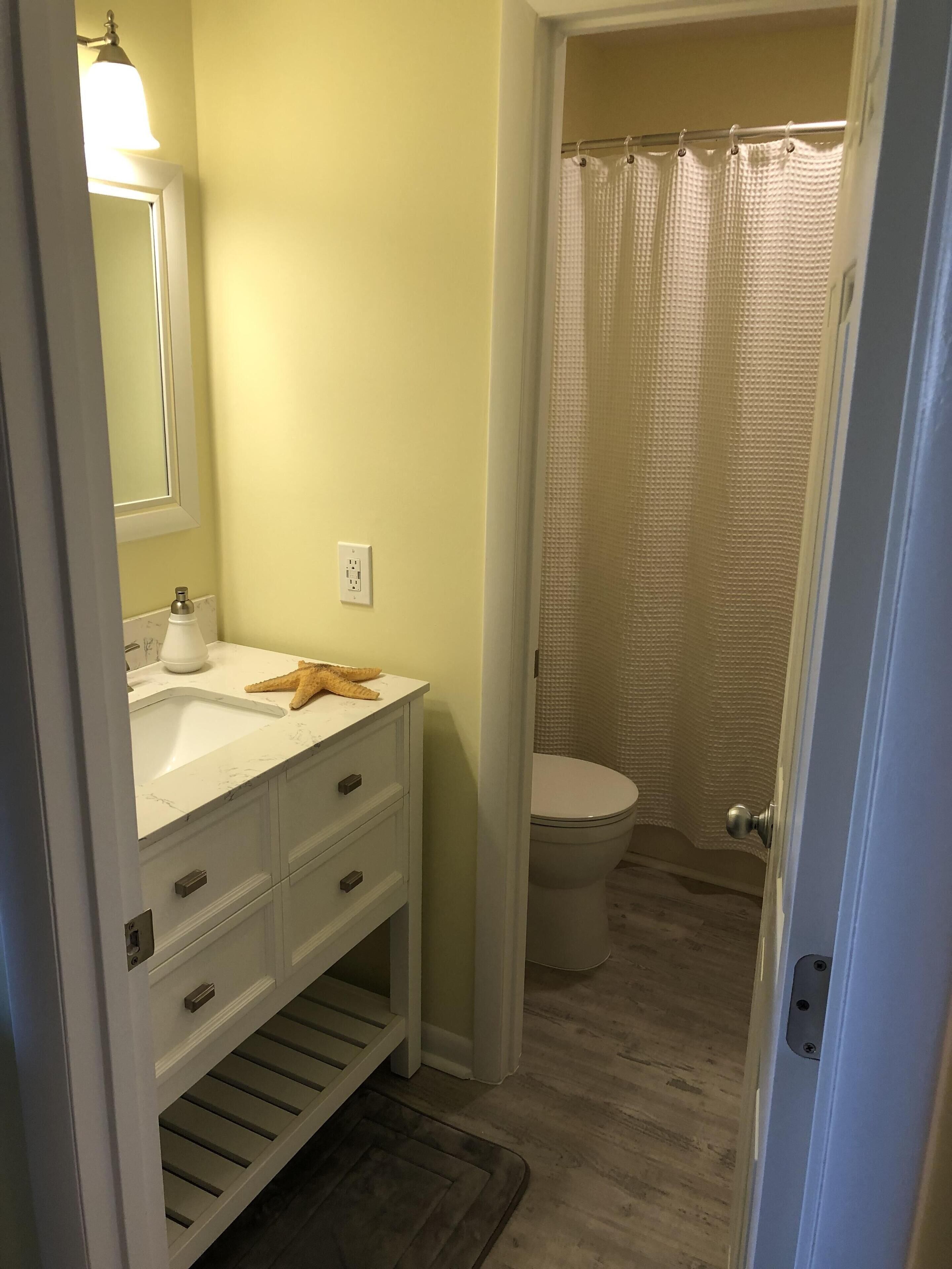 A bathroom with a white sink, a mirror, a towel rack, and a shower curtain.