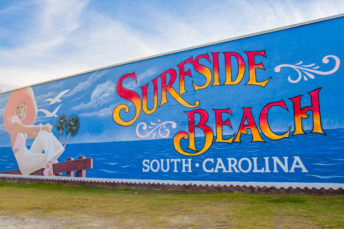 Suurehko seinämaalaus, jossa on kuvattuna nainen rannalla, ja seinässä lukee teksti: »Surfside Beach, Etelä-Carolina».