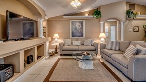 A living room with a flat-screen TV, two sofas, a coffee table, and a fireplace. - Electric heated pool | BBQ | Pet Friendly (Cape Coral)